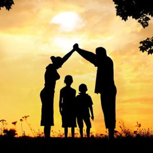 A family standing together, their figures outlined by the sun's rays, creating a beautiful silhouette.