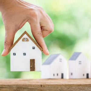 A hand holding a small house model