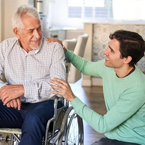 Young man comforting elderly man in wheelchair for emergency guardianship in Texas.